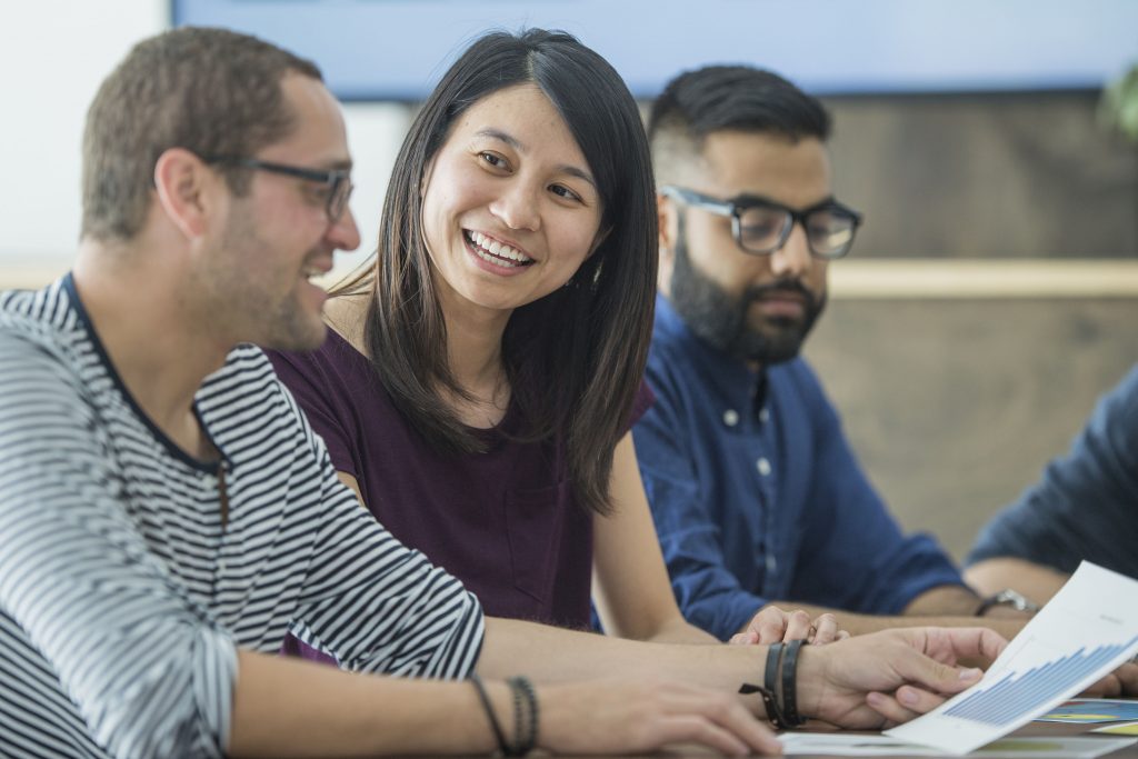 A multi-ethnic group of adult men and women are working indoors.